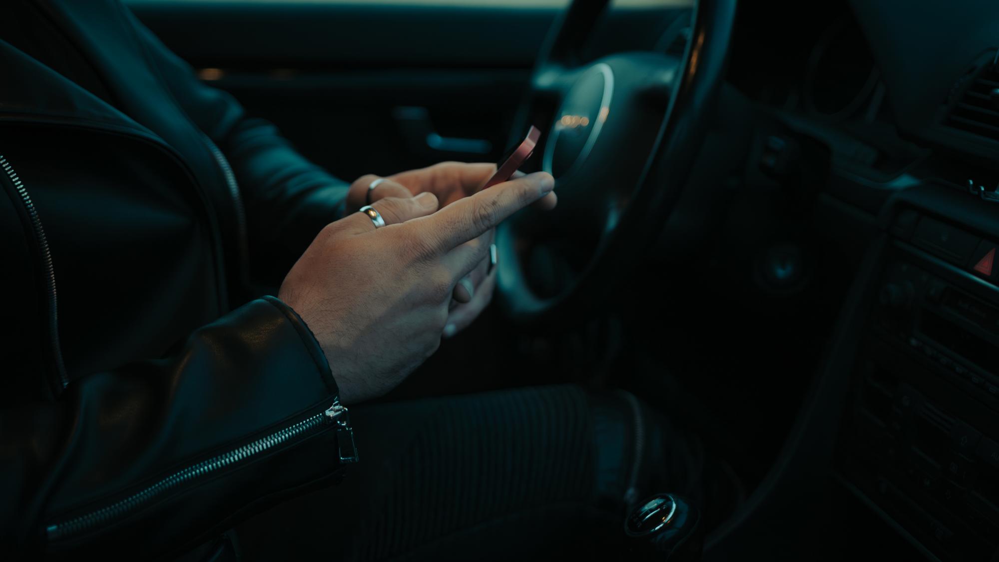 Driver distracted by phone behind the wheel at dusk — Roseville distracted driving lawyers