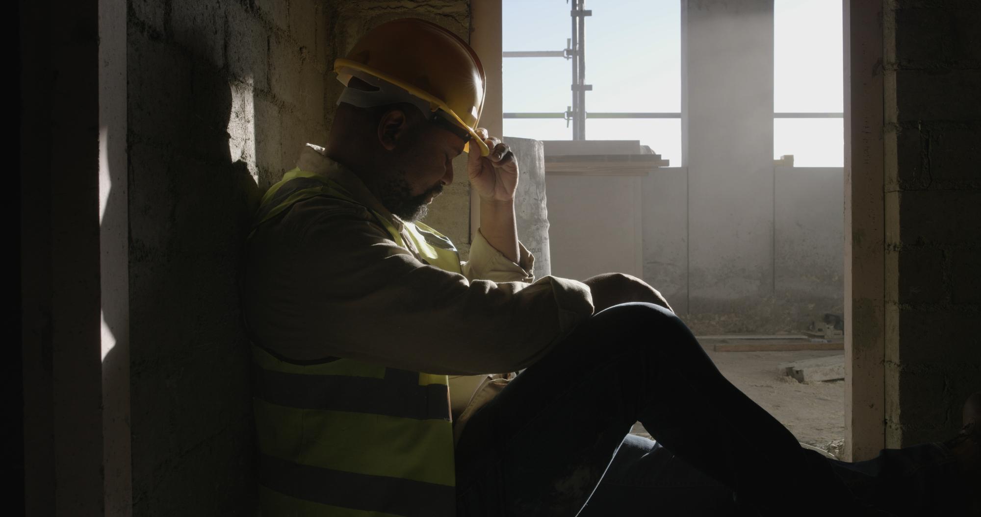 Injured construction worker resting against a wall at a Sacramento, California job site
